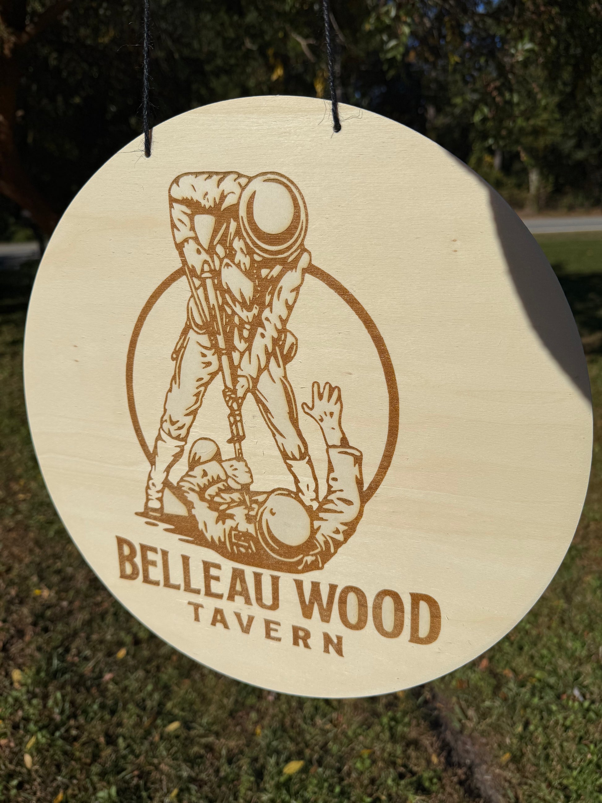 Wooden sign with a engraved illustration and 'Belleau Wood Tavern' text, hanging outdoors.